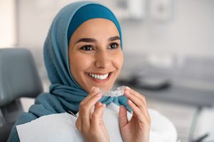 smiling woman holding invisalign plastic tray