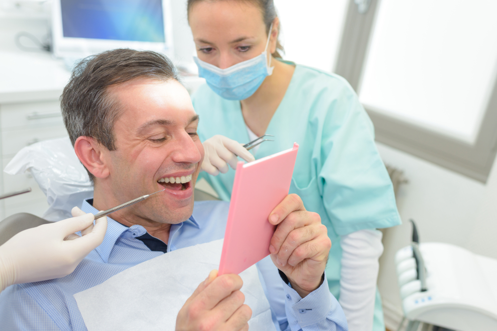 patient with mirror looks at smile