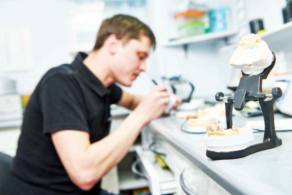 dental technician works on dental prosthesis in dental lab