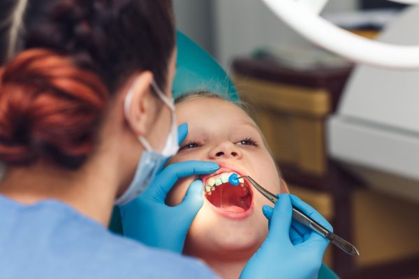 dentist applying fluoride varnish to young patients teeth