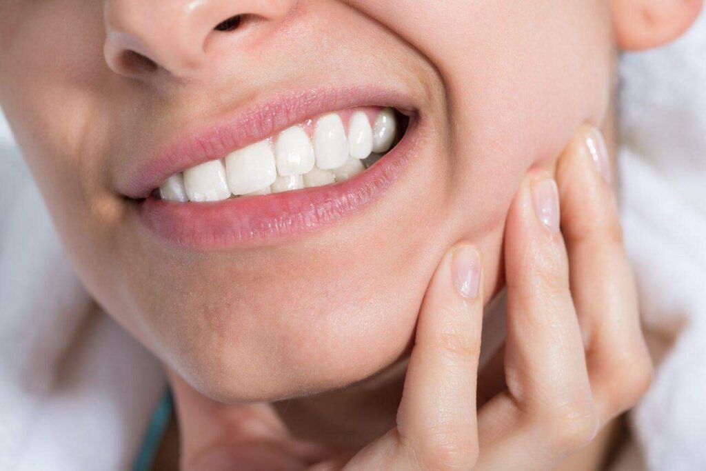 Woman with toothache holding jaw.