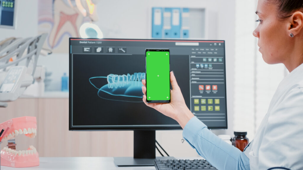 Dentist holding phone with green screen.