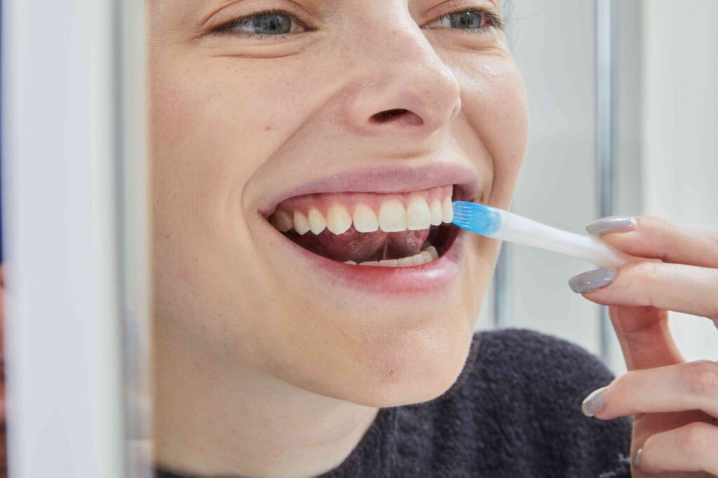 Woman brushing teeth with interdental brush.