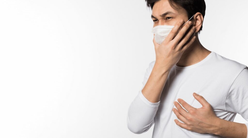 Man in mask, coughing, feeling unwell.
