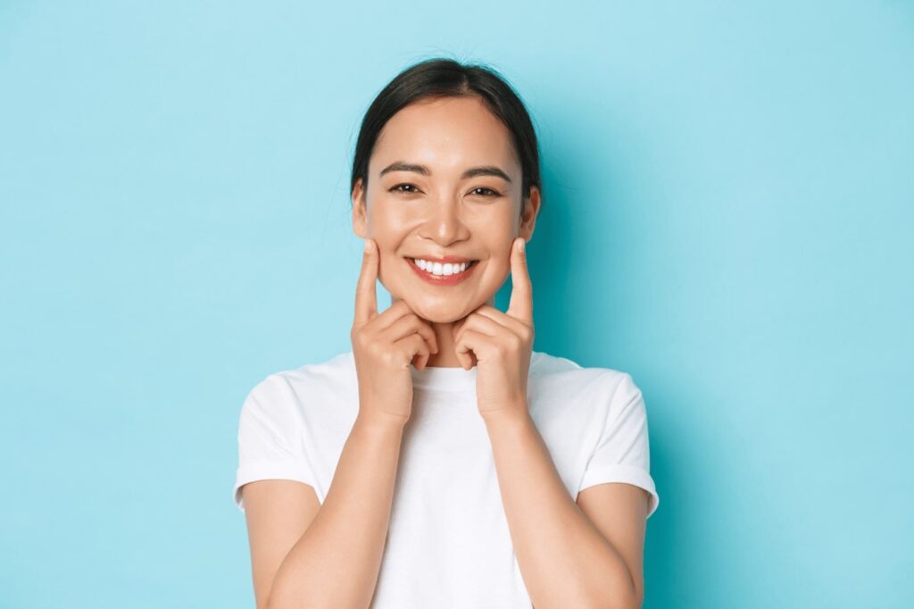Smiling woman touching her face.